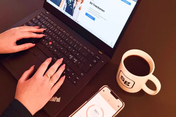 En kvinde, der tjekker sin SU på Skatteguiden appen og er på skatteguiden.dk på sin computer.